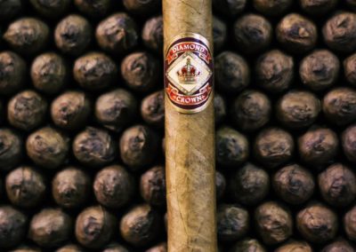 Diamond Crown Cigar Standing in front of piles of rolled cigars