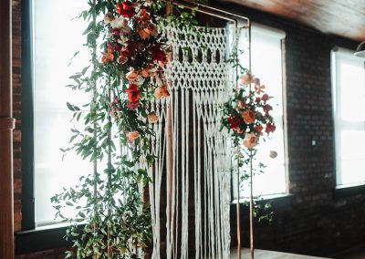 floral and macreme backdrop on wooden event stage in tampa