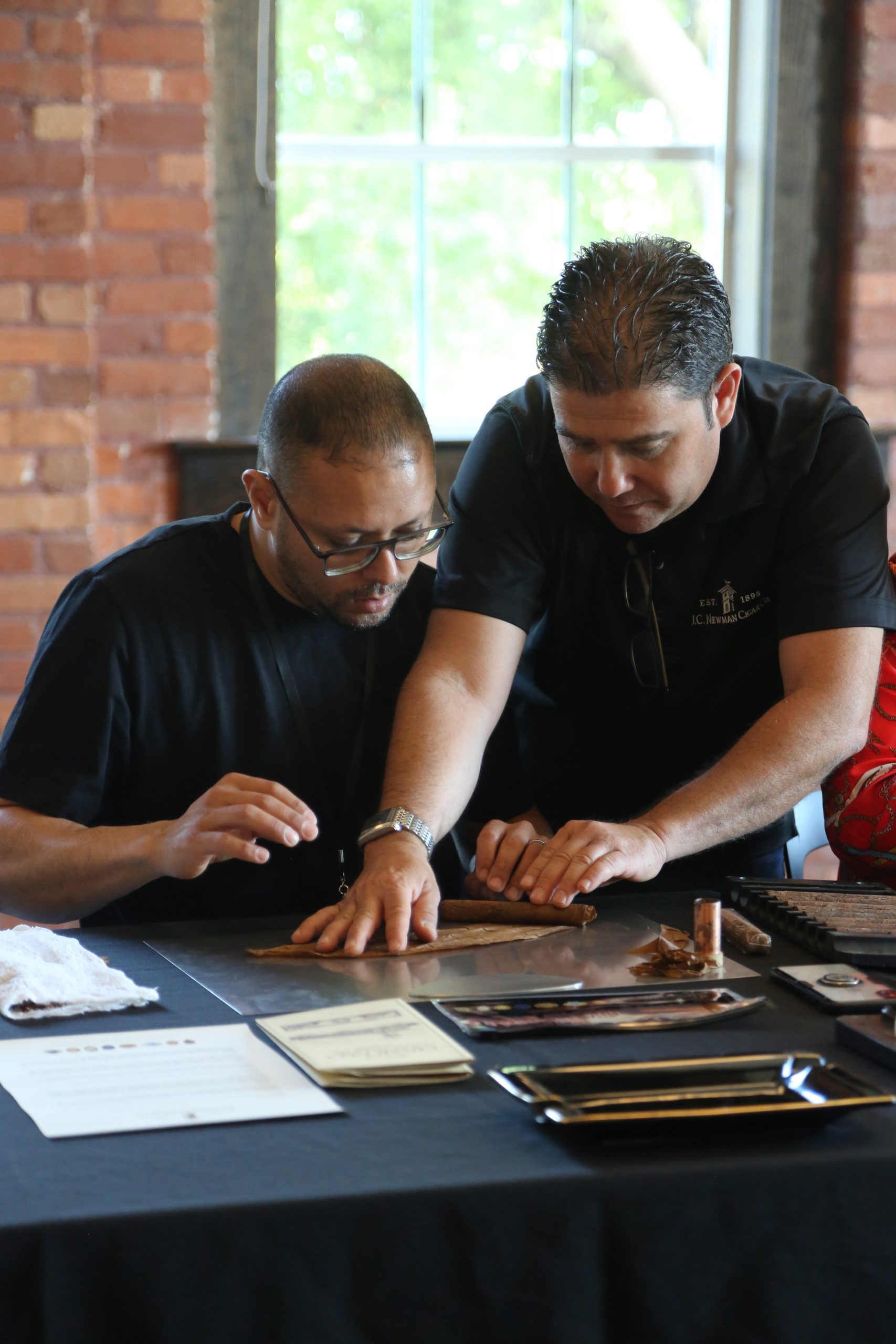 master roller assisting guest in rolling a cigar