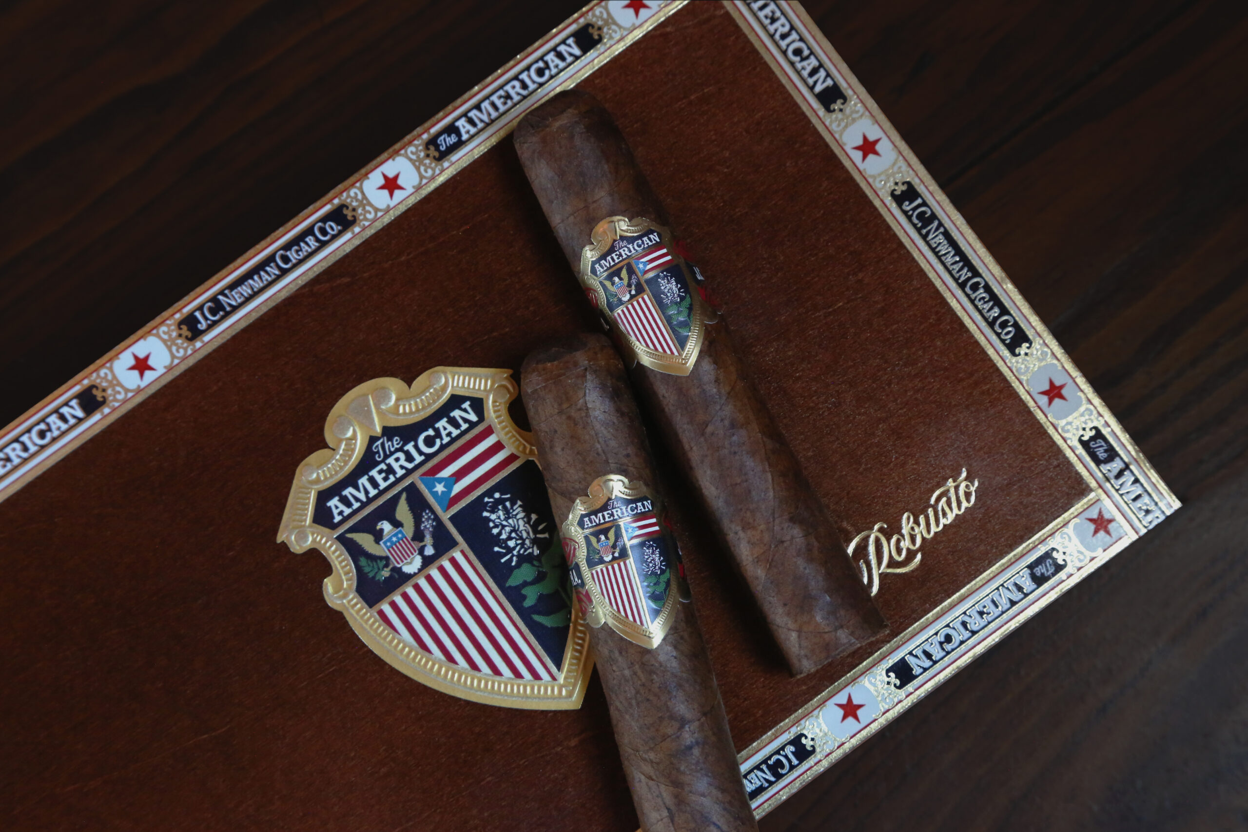 The American Robusto two single cigars atop the american robusto closed cigar box