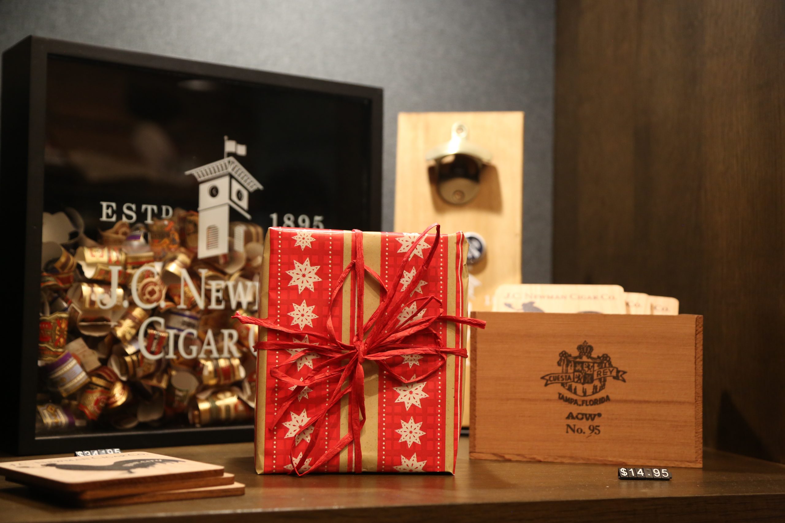 red Christmas package wrapped on a shelf in front of a J.C. newman shadow box and bottle opener