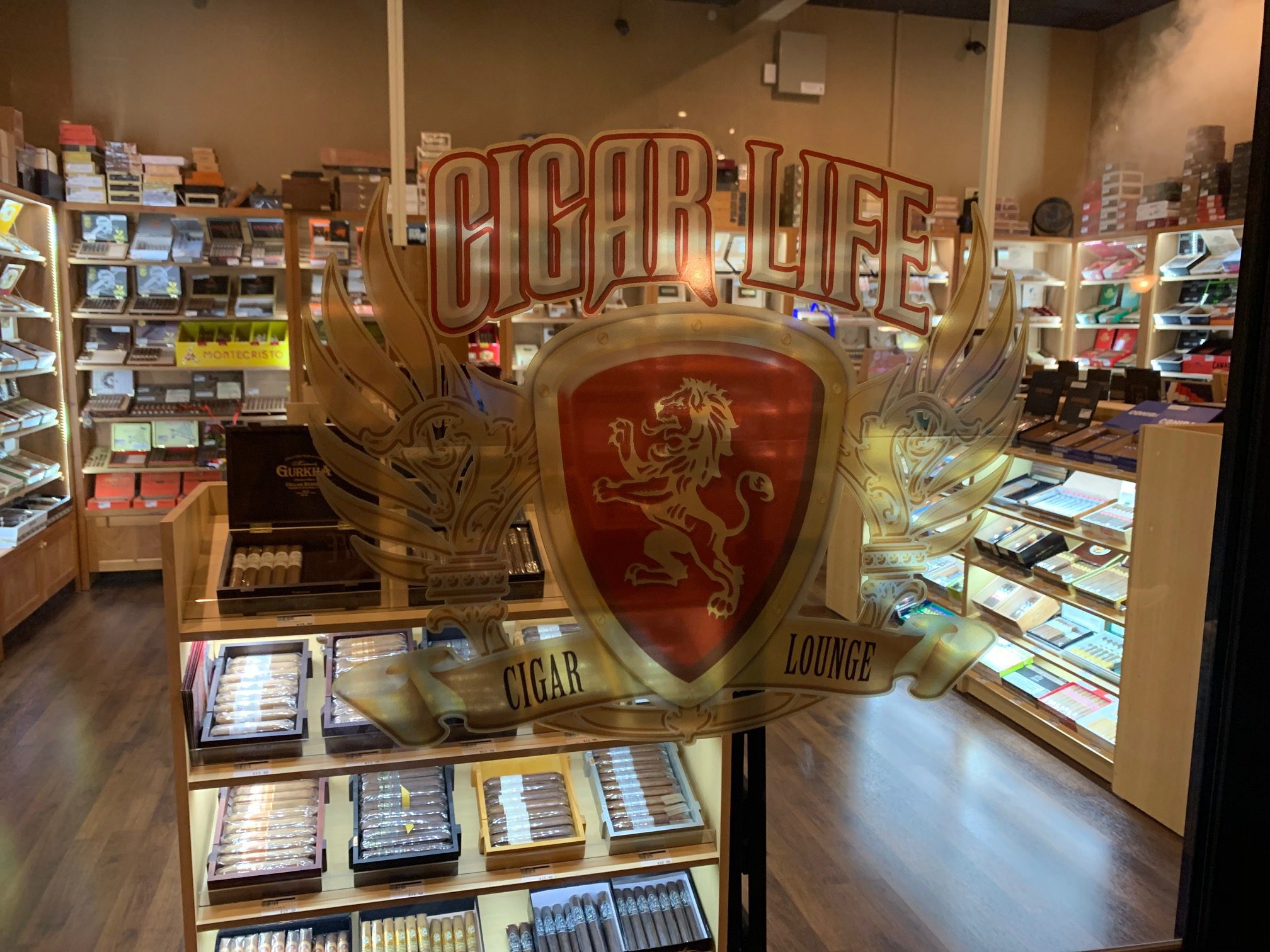 a look inside Cigar Life lakeland cigar shop through their glass door featuring their logo and selection of cigars behind the counter